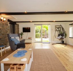 A living room with a sofa and television at Honey Bee Cottage in Menheniot