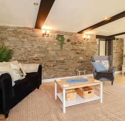 A living room with a sofa and coffee table at Honey Bee Cottage Menheniot
