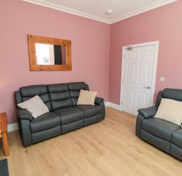 A living room with sofas, a mirror, and a door at Portobell House in Bridlington