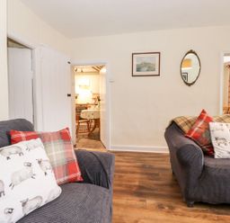 A living room with sofas and a doorway leading to another space at Irt Cottage Seascale