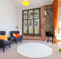 A living room with two chairs and a stained glass window at Flat 16 in Criccieth