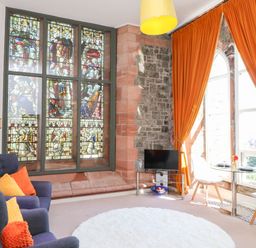 A living room with a stained glass window and sofa at Flat 16 in Criccieth