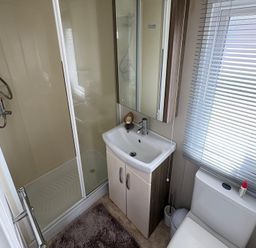 A bathroom with shower, sink, and toilet at Lyons Robin Hood in Rhyl