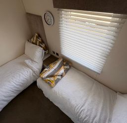 A bedroom with two single beds and a wall clock at Lyons Robin Hood Rhyl