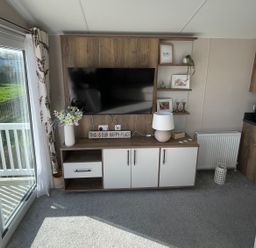 A living room with a television and shelves at Unity Beach Burnham-on-Sea