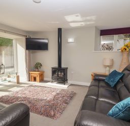 A living room with a television and a stove at The Old Dairy near Liskeard