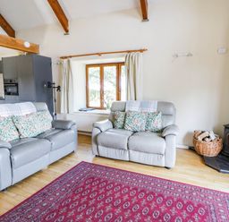 A living room with two sofas and a wood stove at May Cottage St Davids
