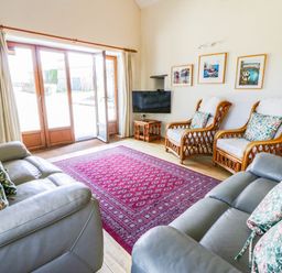 A living room with a sofa and armchairs at May Cottage in St Davids