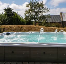 A hot tub with water jets in an outdoor garden at May Cottage St Davids