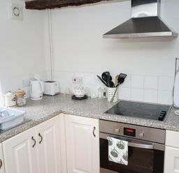 A kitchen with a stove, oven, kettle, dish rack and utensils at The Old Barn in Manchester