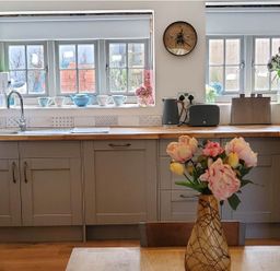 A kitchen with cabinets, sink, and flowers on the countertop at 3 Bedroom Cottage Hot Tub Garden Parking Dunkeswell