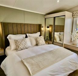 A bedroom with a bed and a side table at Lovely Holiday Home On Waxham Sands in Great Yarmouth