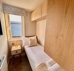 A bedroom with a single bed and lamp at Lovely Holiday Home On Waxham Sands in Great Yarmouth