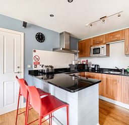 A kitchen with stools and appliances at 2bed sleeps4 pool freeparking Trenythonestate near Par