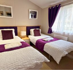 A bedroom with two beds and a nightstand at Meadows 33 Hot tub Southview Holiday Park Skegness