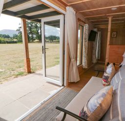 A living room with a sofa and a door leading to a garden at Oak Lodge in Brecon