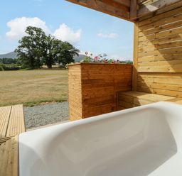 An outdoor bath area with a bathtub and wooden elements at Oak Lodge Brecon