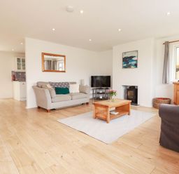 A living room with a sofa, coffee table, and television at Cloudbreak in Wadebridge