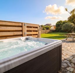 A hot tub and picnic table in an outdoor area at Cloudbreak in Wadebridge