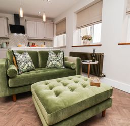 A living room with a green sofa and ottoman at 14 Brunswick Street Whitby