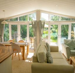 A living room with a sofa and dining table at Ash Lodge in Stowmarket