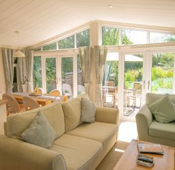 A living room with a sofa and dining area at Ash Lodge in Stowmarket