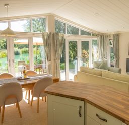 A living room with a dining table and sliding doors at Ash Lodge in Stowmarket