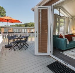 A deck with a table and chairs beside a sofa at 73 Cildraeth in New Quay