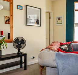 A living room with a mirror, fan, and couch at Seaside Retreat in Newquay