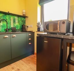 A kitchen with cabinets, a sink, a kettle, a microwave and a refrigerator at The Hyde, Tazamble cottage in Launceston