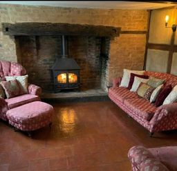 A living room with a pink sofa and armchair near a fireplace at The Old Barn in Manchester