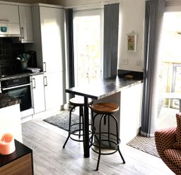 A kitchen with bar counter and stools at Torpoint Apartment Sleeps4 Seaside Parking Downderry