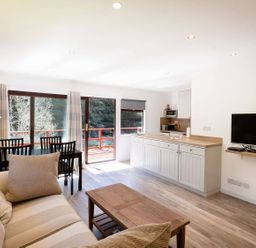 A living room with a kitchen area and dining table at 2 bedroom lodge with free WiFi and mountain view near Crianlarich