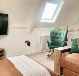 A living room with a television and a rocking chair at Central Tenby 3 Bed Apt Sleeps 6 to 8 Dog Friendly, Tenby