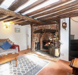 A living room with a fireplace and sofa at Hollyhedge Cottage in Briston