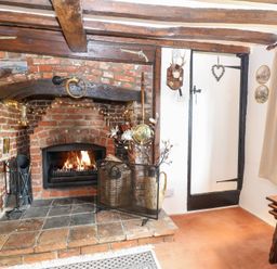 A living room with a fireplace and wooden beams at Hollyhedge Cottage in Briston