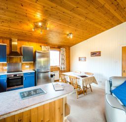 A kitchen with cabinets and a dining table at Raven Lodge with beautiful views of Loch Dochart near Crianlarich
