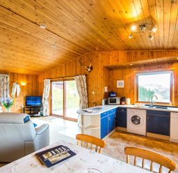 A kitchen with appliances and a dining area at Raven Lodge with beautiful views of Loch Dochart near Crianlarich