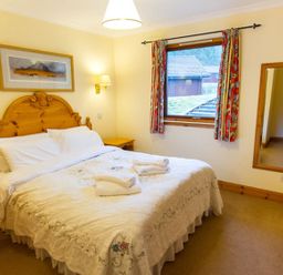 A bedroom with a double bed and a window at Raven Lodge with beautiful views of Loch Dochart Near Crianlarich