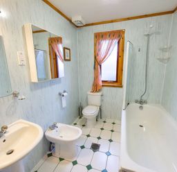 A bathroom with a bathtub, toilet, bidet, and sink at Raven Lodge with beautiful views of Loch Dochart near Crianlarich