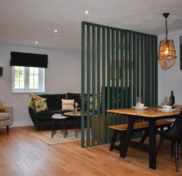 A living room with a sofa and dining area at Yr Hen Beudy Barn Conversion Sleeps 4 Dogs Ok near Brodle Farm near Llansteffan