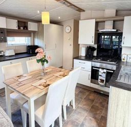 A kitchen with table and chairs at Lillardsedge Luxury Caravan Sleeps 6 with Parking near Lilliardsedge Holiday Park