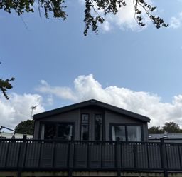 A cabin with decking and chimney at Harrogate Lodge Sleeps4 South Facing Decking Lufflands Caravan Park near Holsworthy