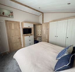 A bedroom with a bed, television, and storage furniture at Harrogate Lodge Sleeps4 South Facing Decking Lufflands Caravan Park near Holsworthy