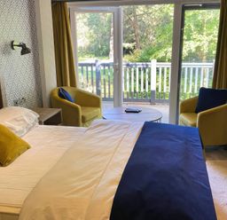 A bedroom with a bed and chairs at Sandy Balls Holiday Park Pet Friendly Lodge in Godshill, Hampshire