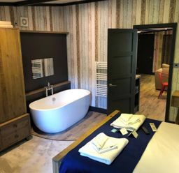 A bathroom with a bathtub and wardrobe at Sandy Balls Holiday Park Pet Friendly Lodge in Godshill, Hampshire