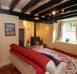 A living room with a sofa and stove at Felin Bach in Aberdaron