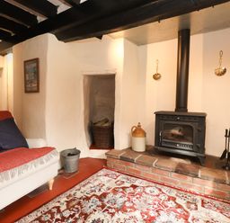 A snug with a stove and sofa at Felin Bach in Aberdaron