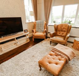 A living room with a television, two armchairs, and a coffee table at 11 Bryn Goleu Avenue North in Holyhead