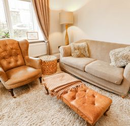 A living room with a sofa, armchair, and lamp at 11 Bryn Goleu Avenue North in Holyhead